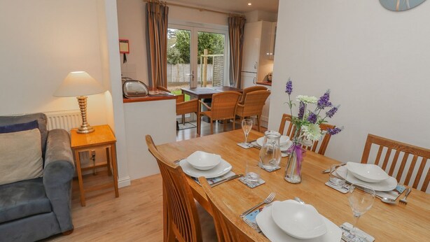 A dining area with a wooden table set for four, a grey sofa, and a lamp. - Pierpont D1 (Yarmouth)
