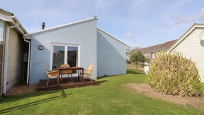 A small, light blue house with a patio area featuring a table and chairs. - Pierpont D1 (Yarmouth)