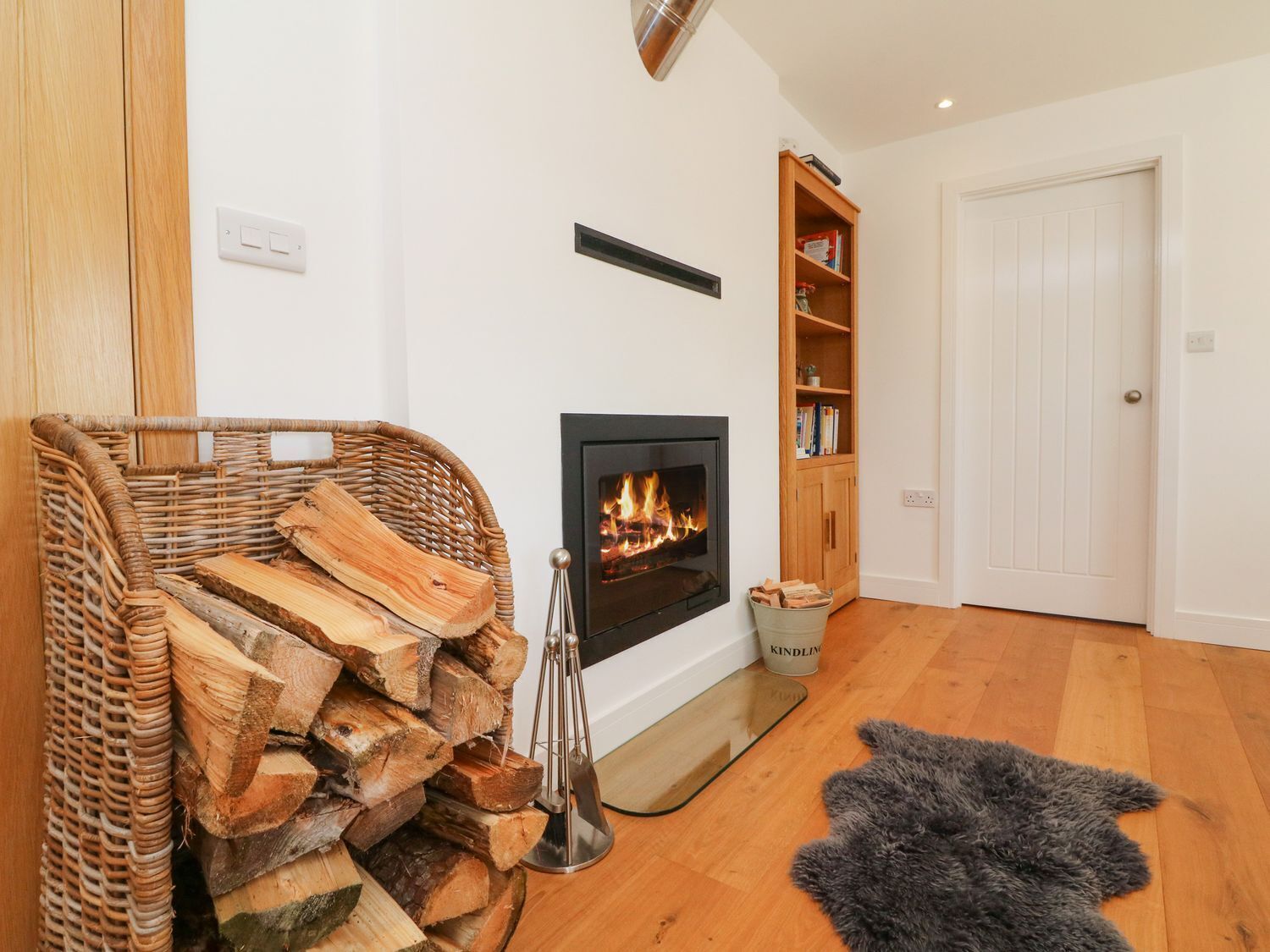 Una sala de estar con chimenea, estantería y una puerta.
