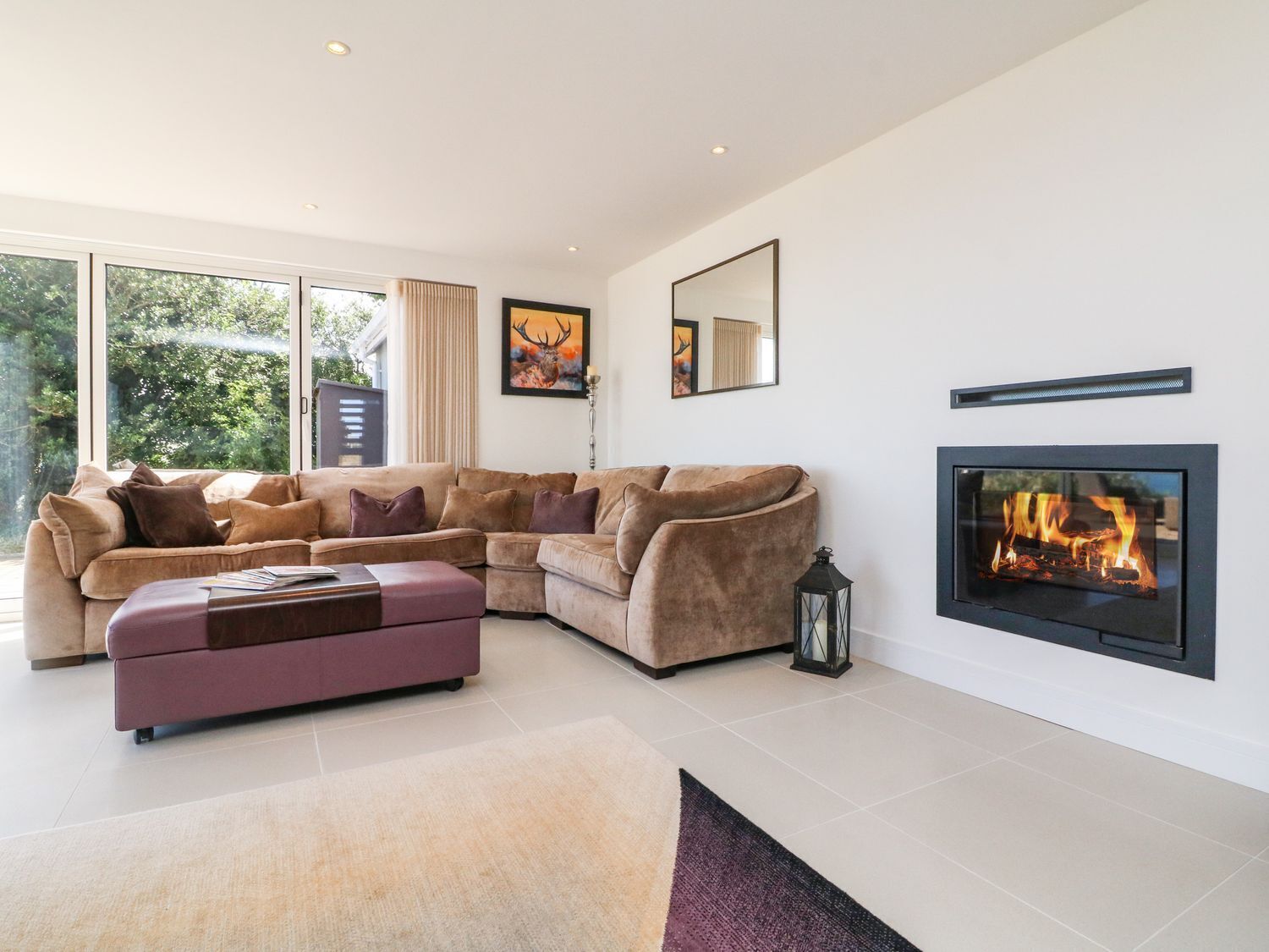 A modern living room with a sectional sofa, a fireplace, and large windows.