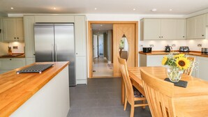 Een moderne keuken met een centraal eiland, roestvrijstalen apparatuur en een eetgedeelte met een houten tafel en stoelen.