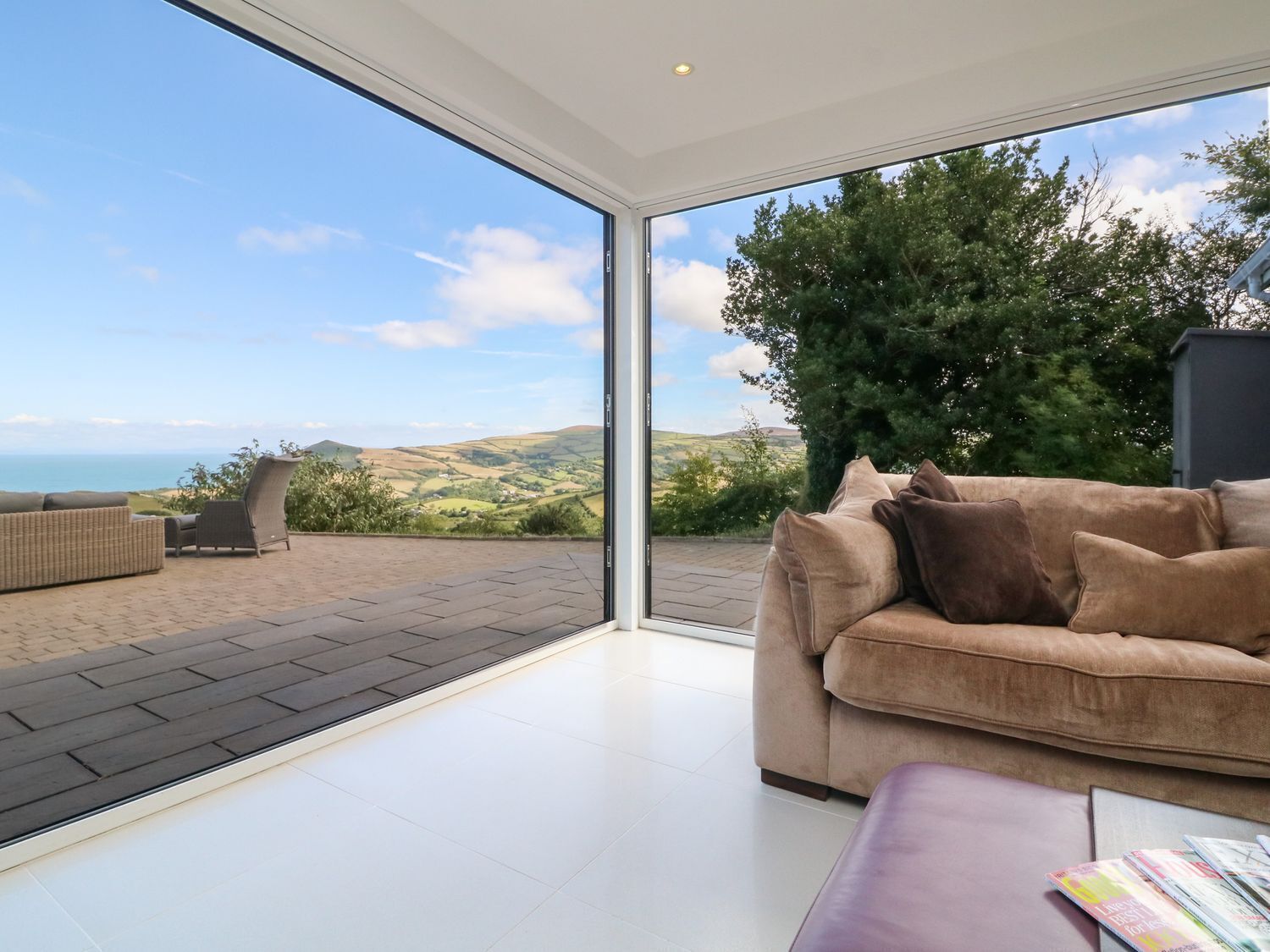A modern living room with a large glass door leading to an outdoor patio.