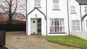 A two-story residential building with a white exterior, a black roof, and a small front porch with steps leading to the door marked with the number 29. - Portstewarts Home From Home (Portstewart)