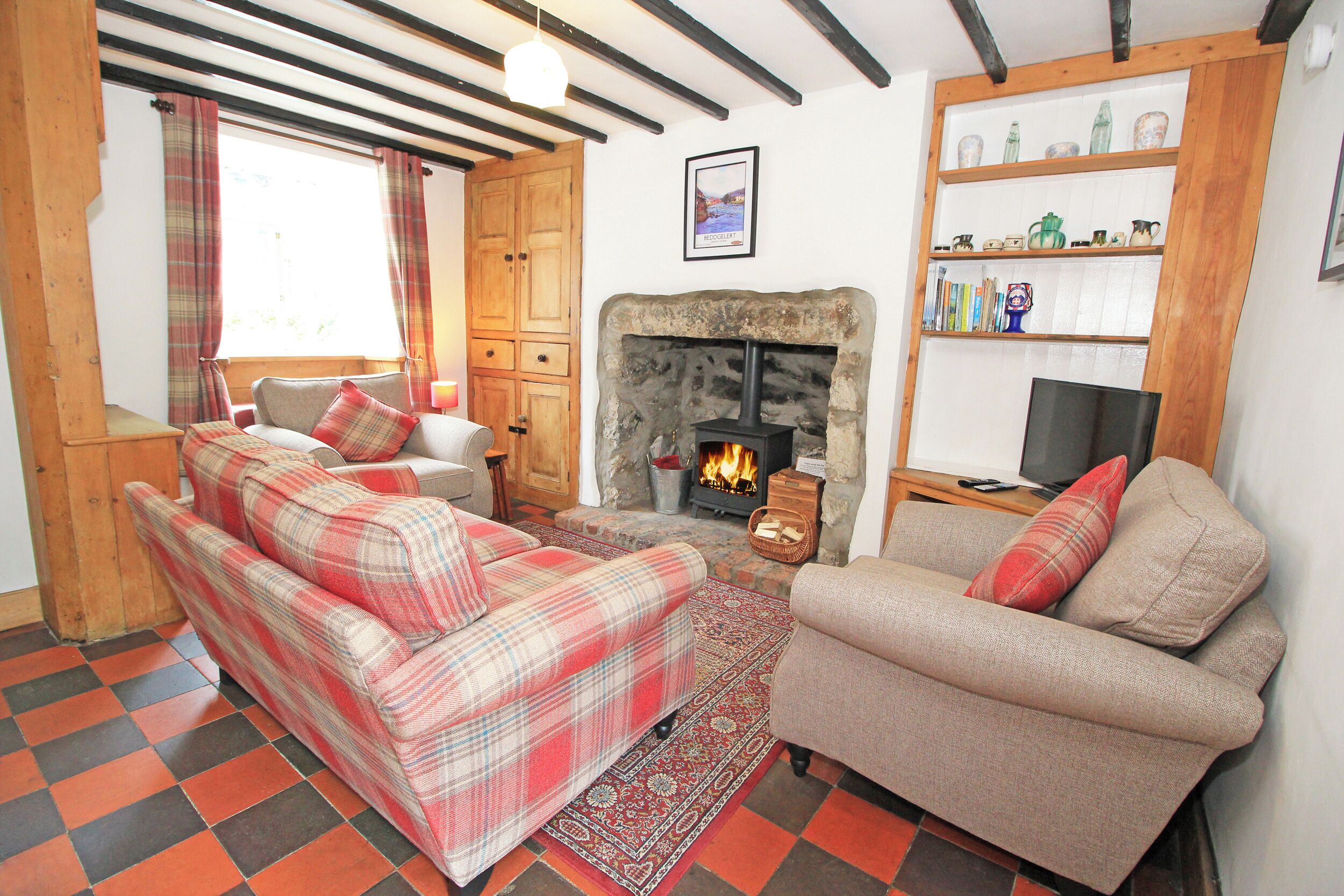 A cozy living room with a fireplace, two sofas, a wooden cabinet, and a bookshelf.