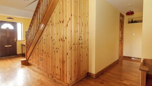 Une pièce spacieuse dotée d’un plancher en bois, d’un escalier en bois et d’une porte donnant sur un autre espace.