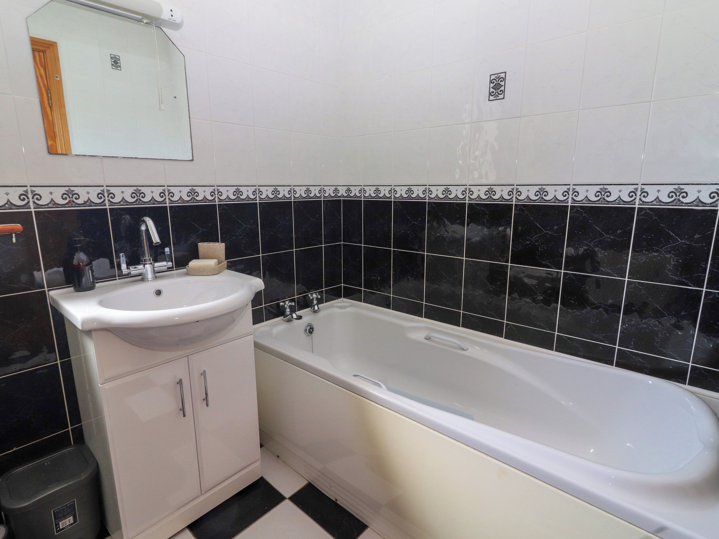 Ein Badezimmer mit einem weißen Waschbecken, einer Badewanne und schwarzen Marmorfliesen.