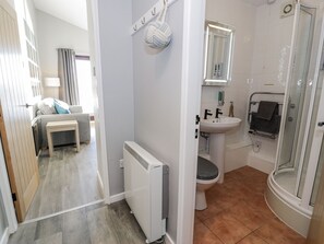 A compact bathroom with a toilet, sink, and shower. - Estuary Escape (Porthmadog)