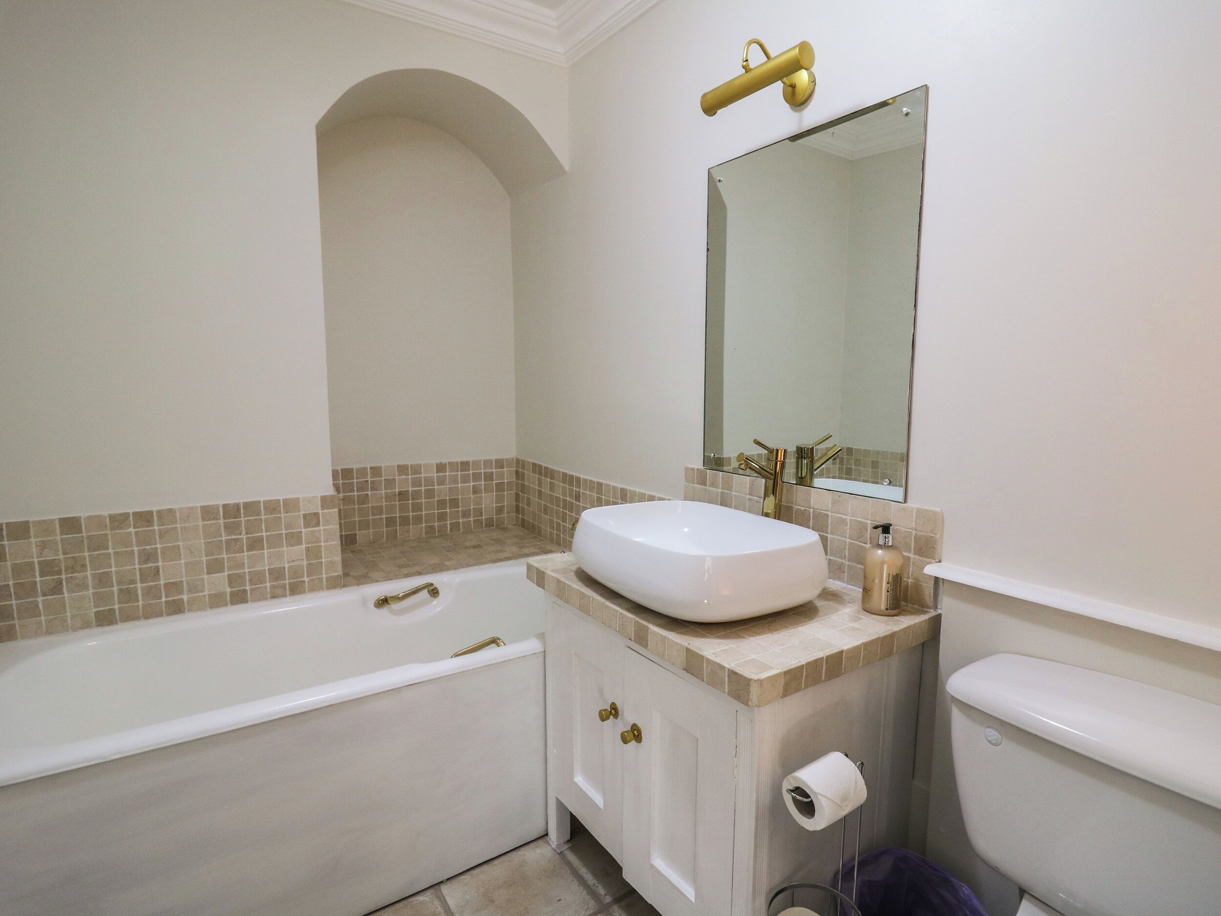 Une salle de bain avec une baignoire blanche, un lavabo avec un miroir au-dessus, et des toilettes.