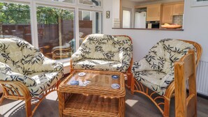 A sunlit room with wicker furniture, large windows, and a view of the outdoors. - Craggy View (Kendal)