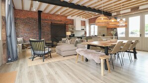 A modern kitchen with a brick wall, wooden beams, and a large window. - Rowan Cottage - Fold Yards (Matlock)