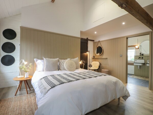 Une chambre à coucher avec un grand lit, une table de chevet avec une lampe, une chaise et un miroir.