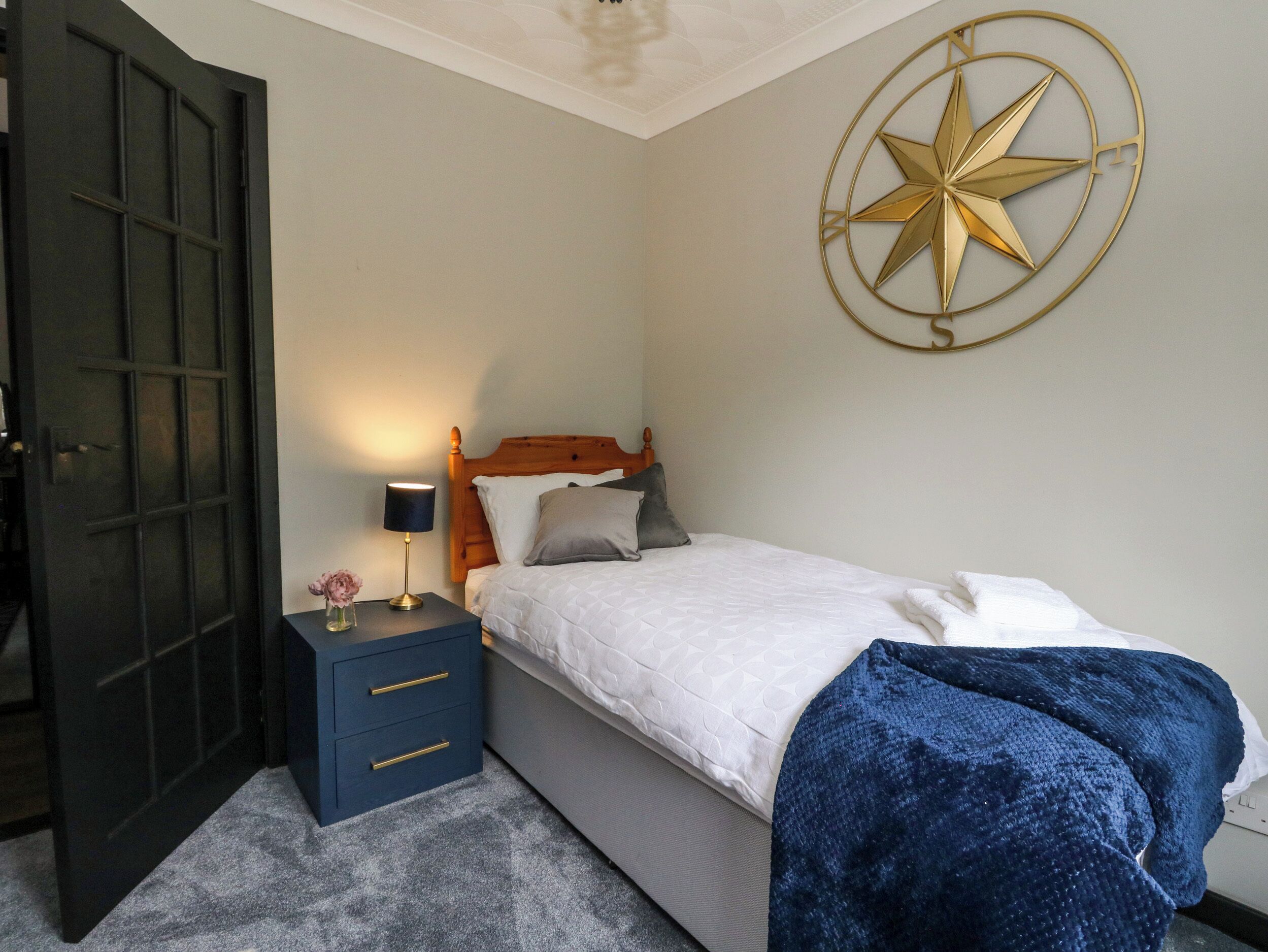 A bedroom with a bed, a nightstand, a wall-mounted star decoration, and a door.