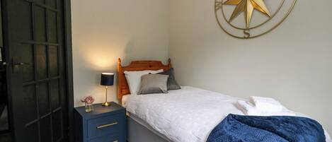 A bedroom with a bed, a nightstand, a wall-mounted star decoration, and a door.