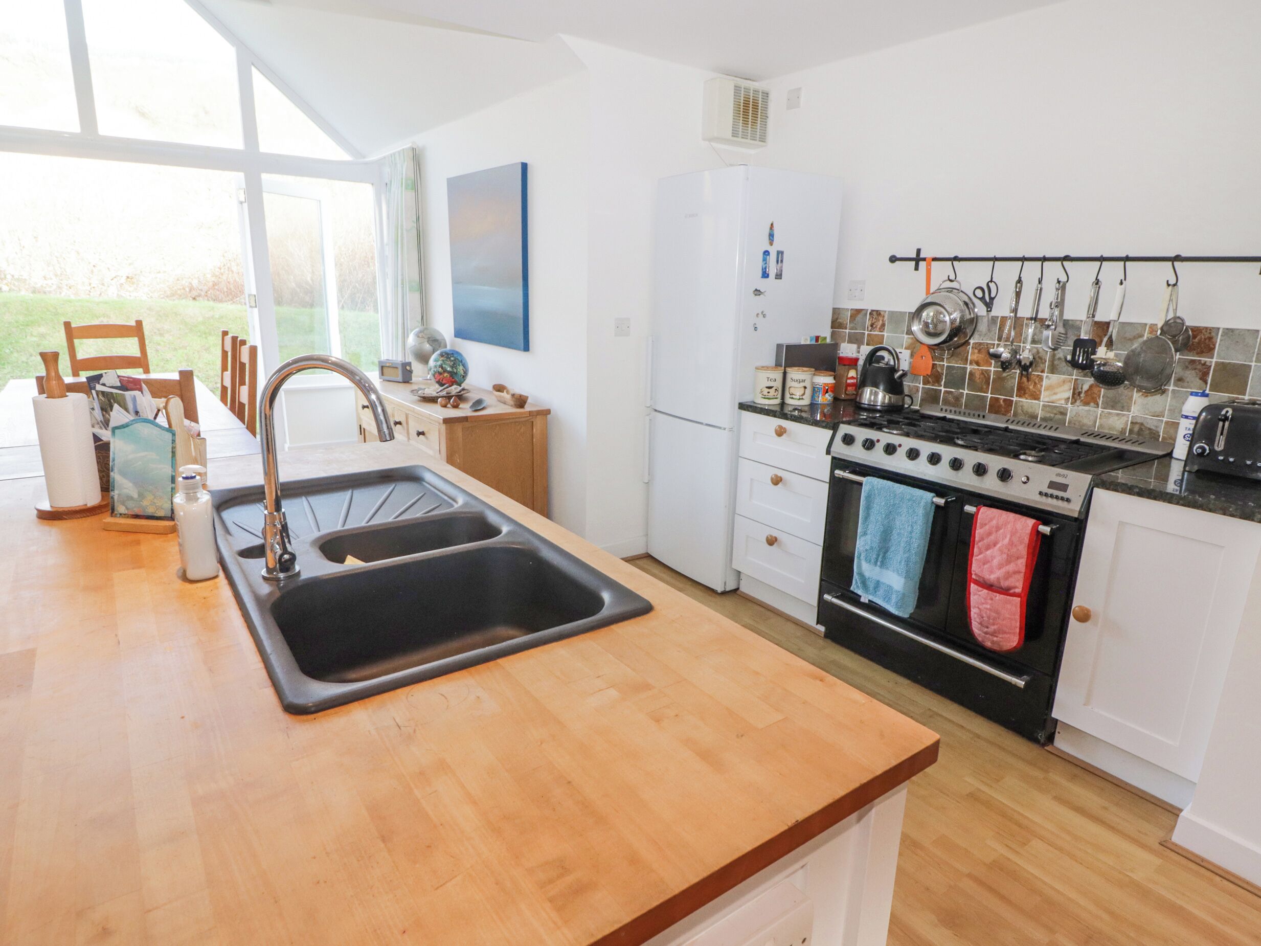 Een moderne keuken met een houten aanrecht, een dubbele spoelbak, een fornuis en een koelkast.