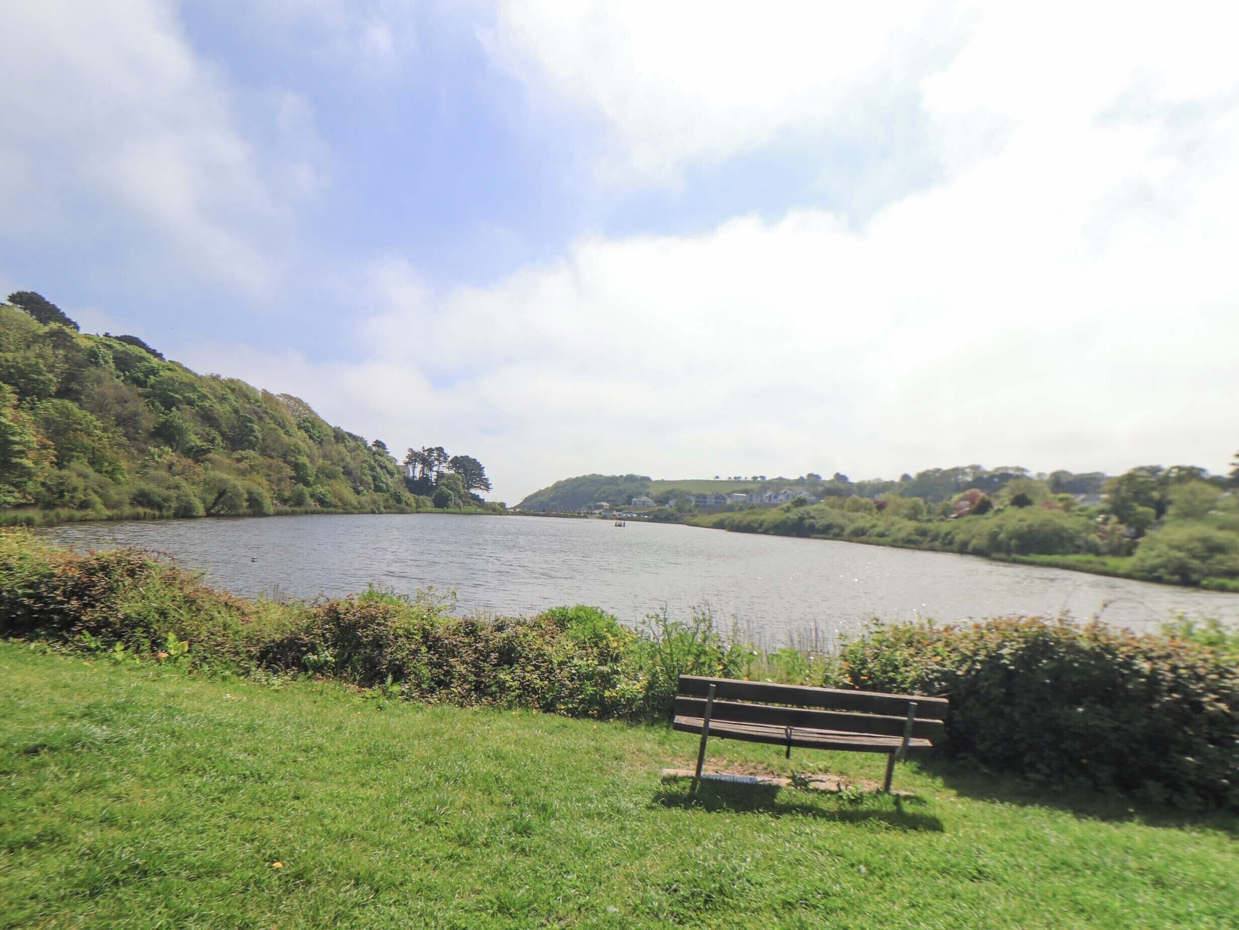 A bench by a lake with hills in the background.