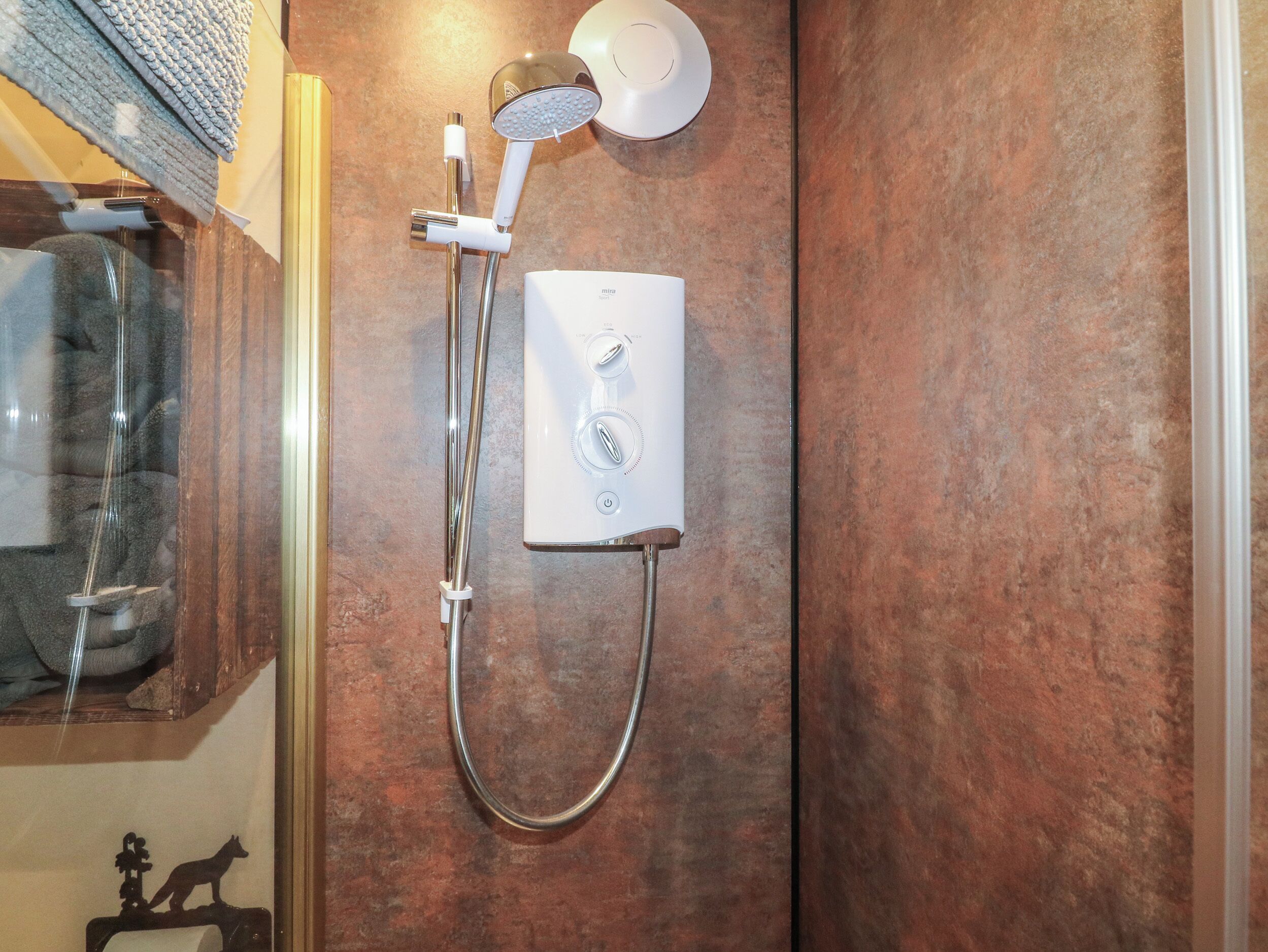 A shower with a handheld showerhead and a wall-mounted control panel.