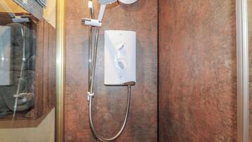 A shower with a handheld showerhead and a wall-mounted control panel.