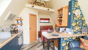A compact kitchen with a dining area, a sofa, and a clock on the wall. - Sunflower Lodge (Doncaster)