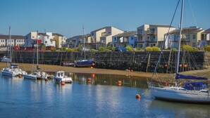 A marina with boats docked, a stone wall, and residential buildings in the background. - 66D South Snowdon Wharf (Porthmadog)