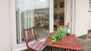 A wooden table with a chair, a bottle, and a plant outside a building. - 66D South Snowdon Wharf (Porthmadog)