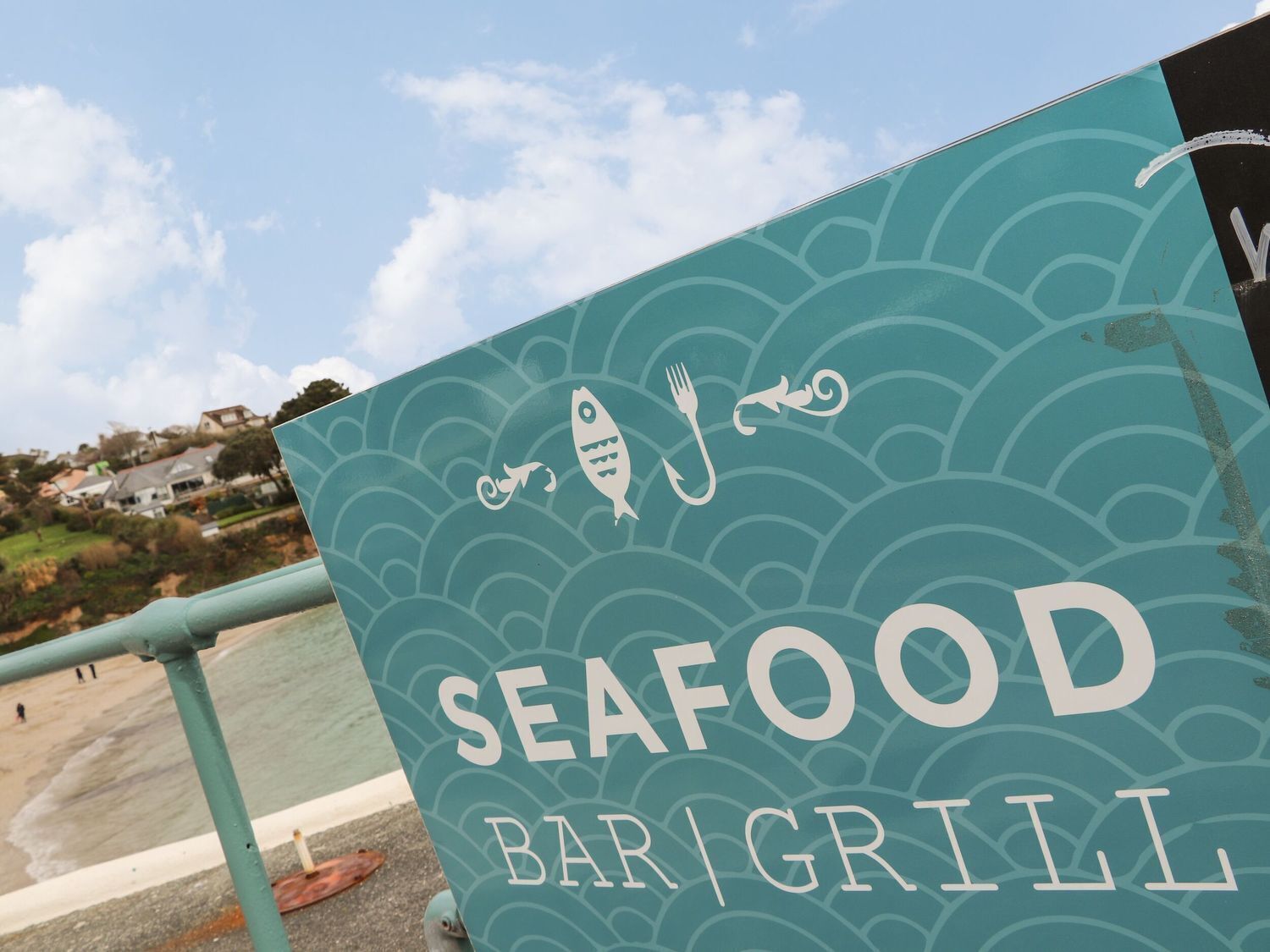 A sign for a seafood bar and grill with a coastal view.