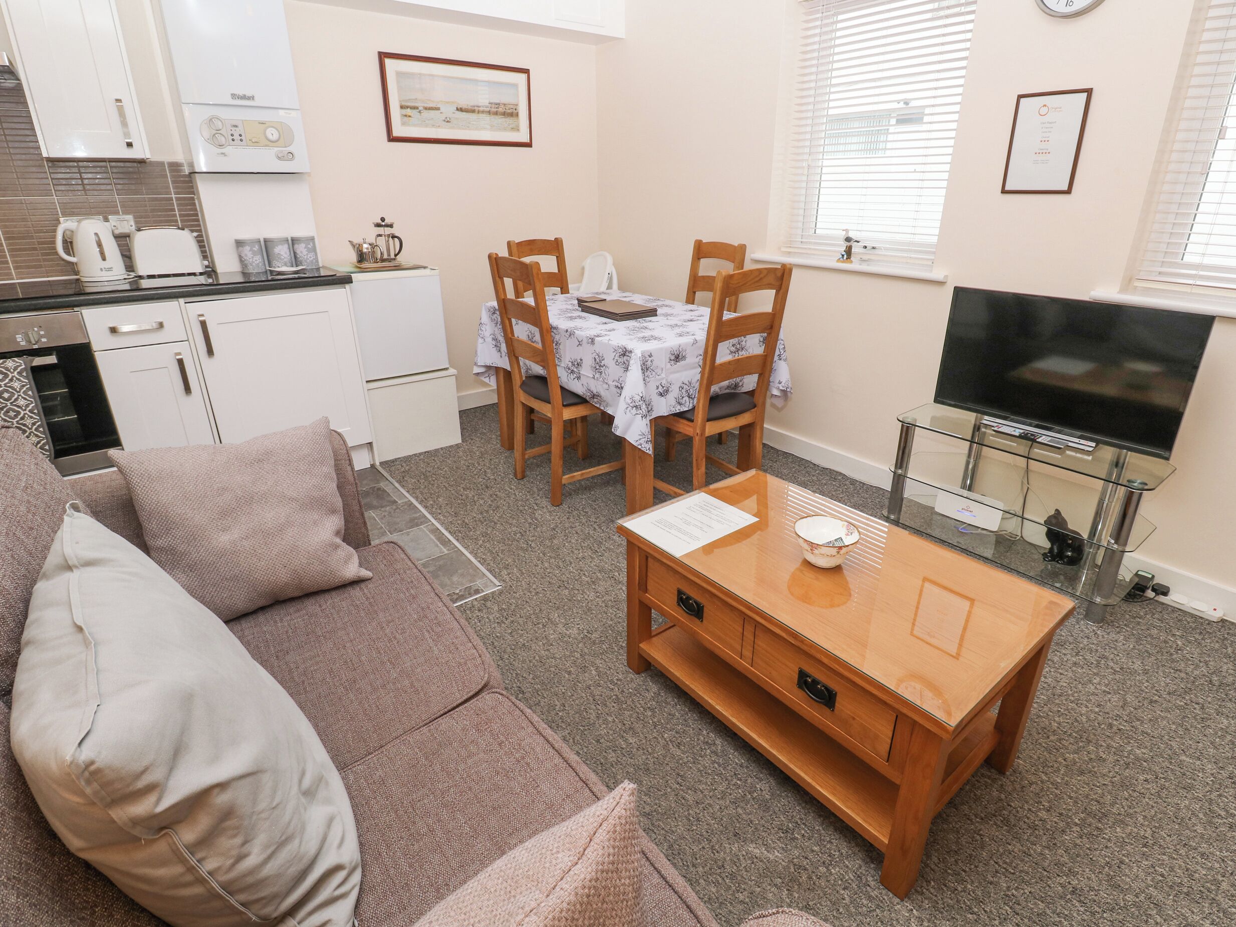 A compact living space with a kitchenette, a dining area, a sofa, and a TV.