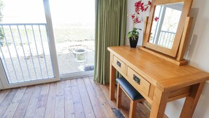 A wooden vanity with a mirror, a bench, and a potted plant. - Heron's Den (Horncastle)