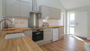 Een moderne keuken met houten aanrechtbladen, roestvrijstalen apparatuur en lichtkleurige kastjes.