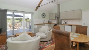 Een moderne keuken met witte kasten, een roestvrijstalen afzuigkap en een eethoek met een houten tafel en stoelen.