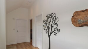 A hallway with wooden flooring, white walls, and a black tree decal. - Doubletree Cottage (Warminster)