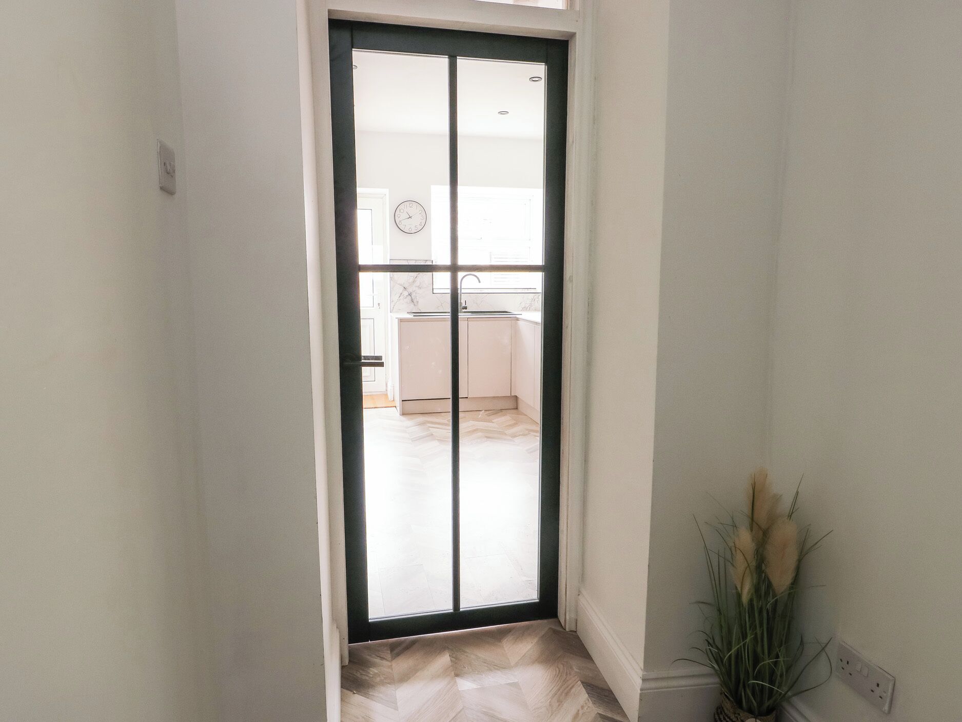 A narrow hallway with a sliding glass door leading to a kitchen area.