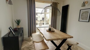 Ein stilvoller Essbereich mit Holztisch, Bänken, einem Blumentopf und Blick durch das Fenster.