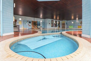 An indoor swimming pool with a tiled floor and a wooden ceiling.