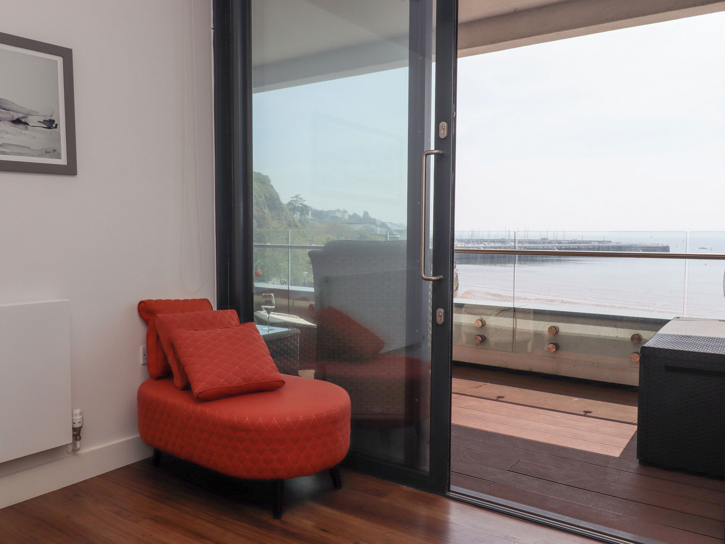 Una camera moderna con una porta scorrevole in vetro che dà su un balcone con vista sul mare.