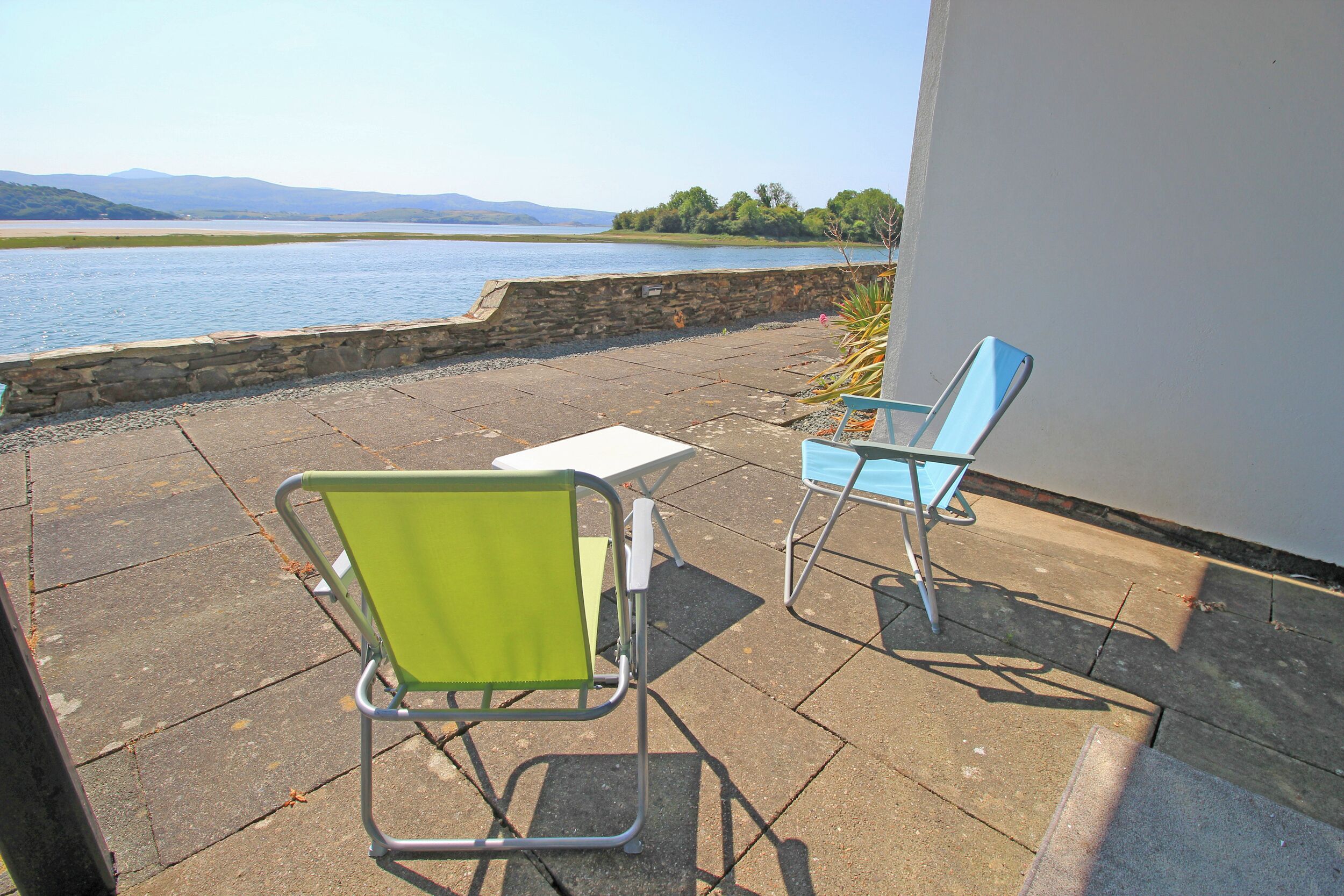 Een terras met twee stoelen en een tafel met uitzicht op water.