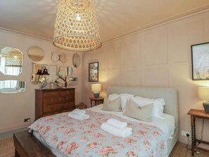A bedroom with a bed, bedside lamps, a dresser, and a hanging light fixture. - Cotswold House (Moreton-in-Marsh)