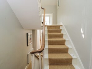 A staircase with a wooden handrail and beige carpeted steps. - Cotswold House (Moreton-in-Marsh)
