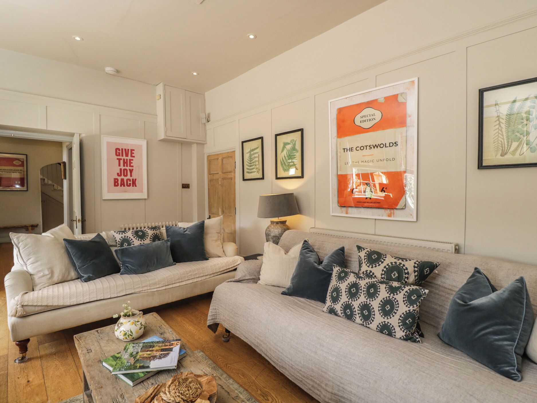 A living room with two sofas, a coffee table, and framed botanical prints on the wall.