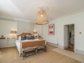 A bedroom with a bed, bedside lamps, a hanging light fixture, a framed poster, and a radiator. - Cotswold House (Moreton-in-Marsh)