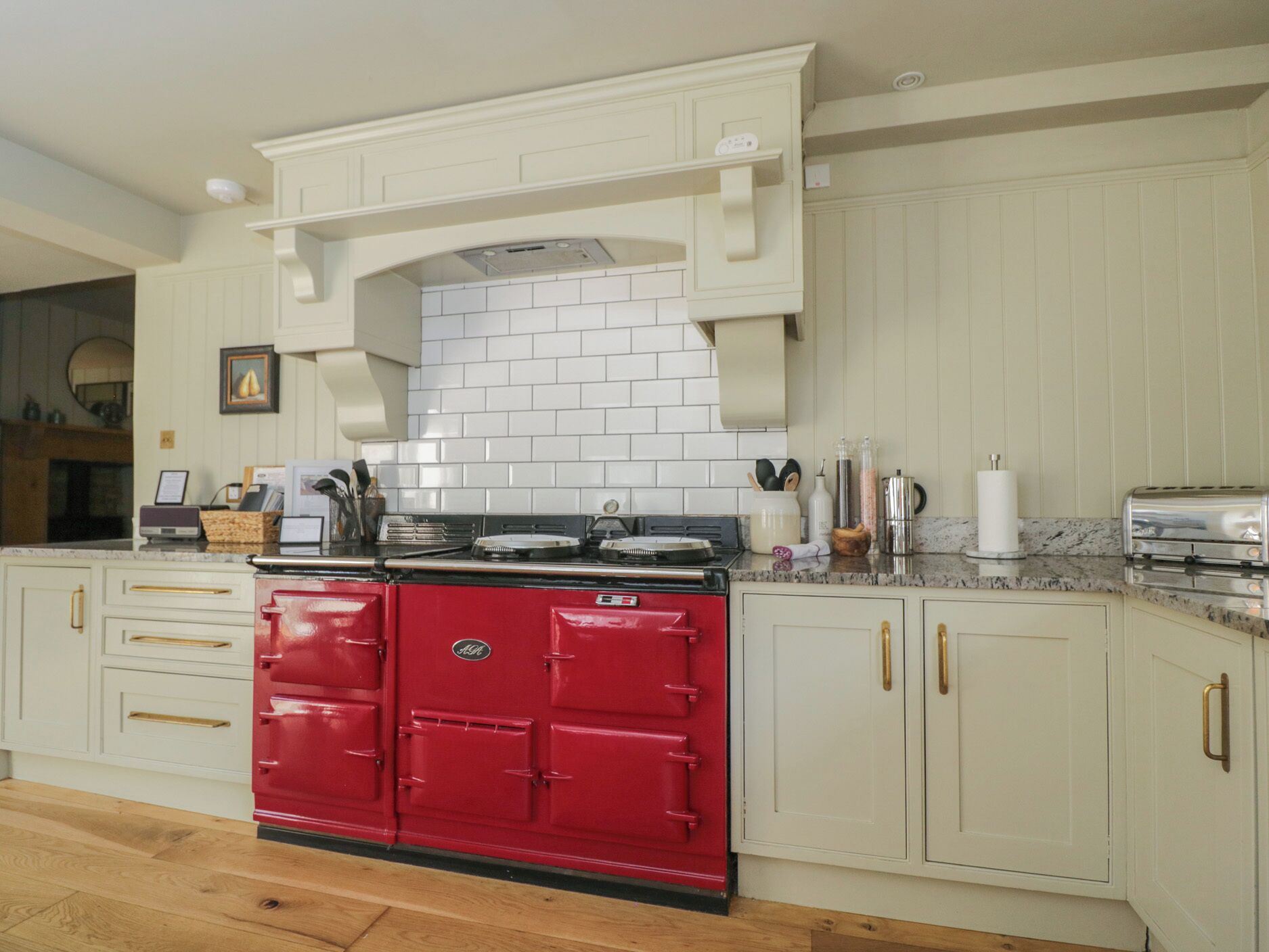 A kitchen with white cabinetry, a red stove, and a tiled backsplash.