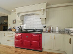 A kitchen with white cabinetry, a red stove, and a tiled backsplash. - Cotswold House (Moreton-in-Marsh)