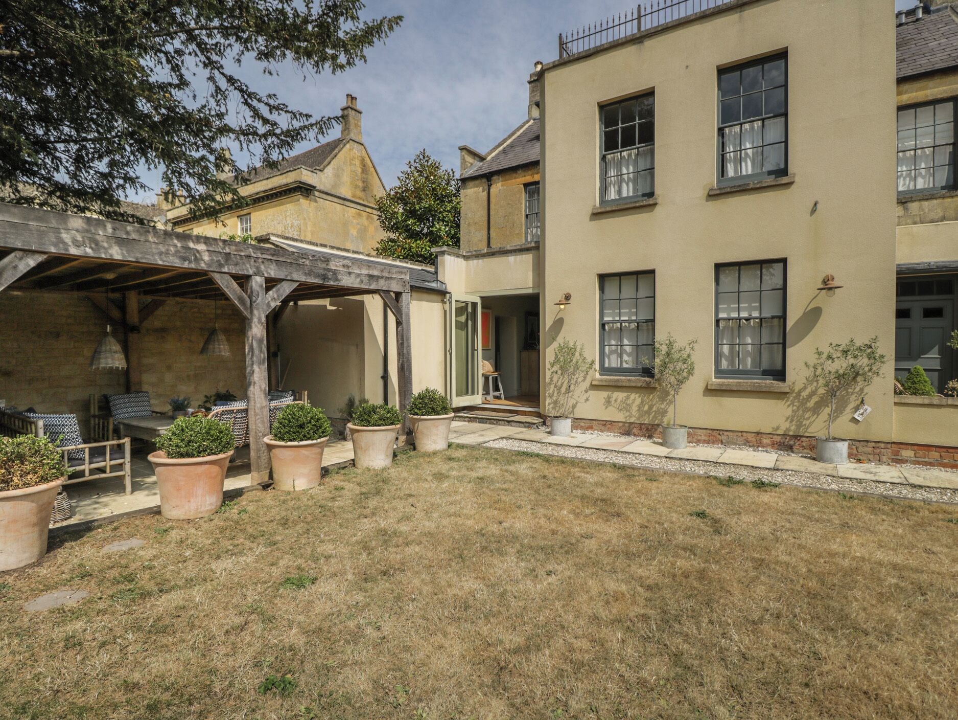 Ein Innenhof mit einer Pergola, Blumentöpfen und einem Gebäude mit zahlreichen Fenstern.