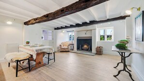 Una habitación amplia con techo alto, vigas de madera a la vista, chimenea y un rincón de descanso acogedor.