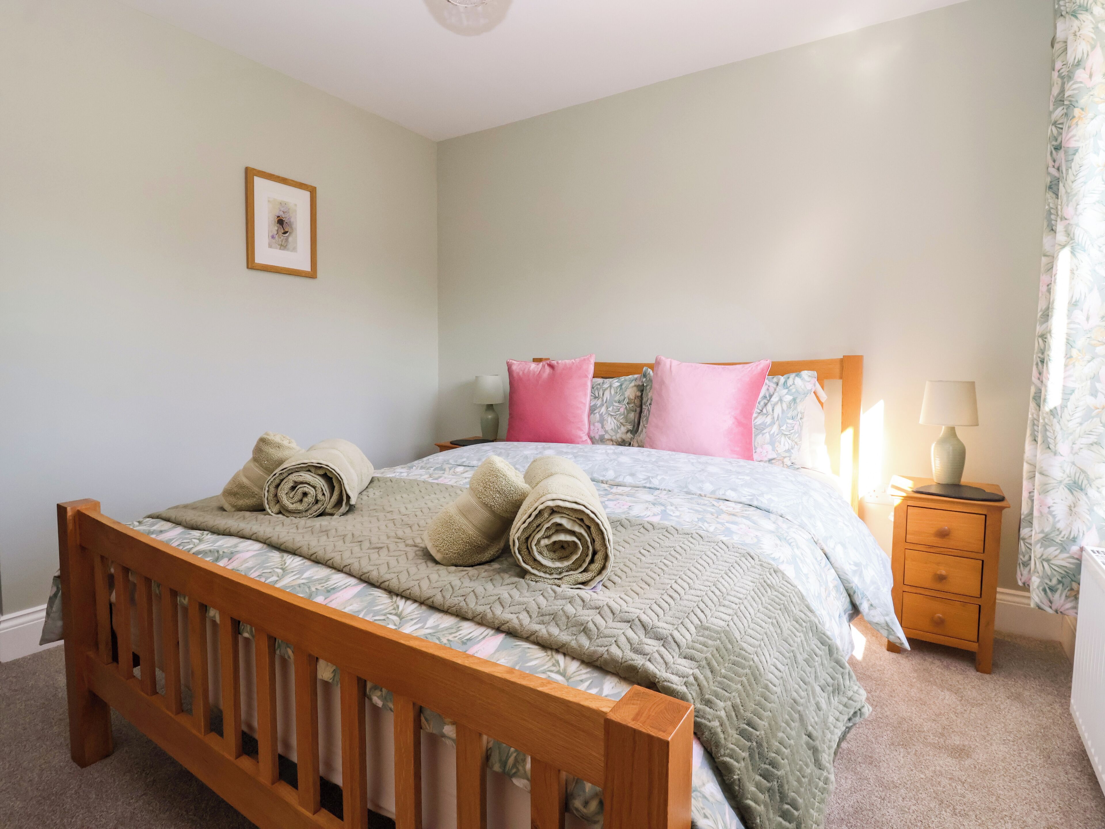 Una camera da letto con un letto in legno, un comodino con una lampada e un quadro appeso al muro.