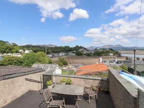 A rooftop terrace with a table and chairs, overlooking a residential area and a body of water. - The Quarterdeck (Porthmadog)
