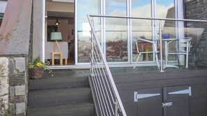 Un bâtiment moderne doté d’une façade en verre, d’un escalier menant à une terrasse et de mobilier d’extérieur.