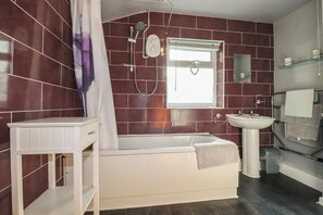 Un bagno con vasca, doccia, lavabo con specchio e finestra.