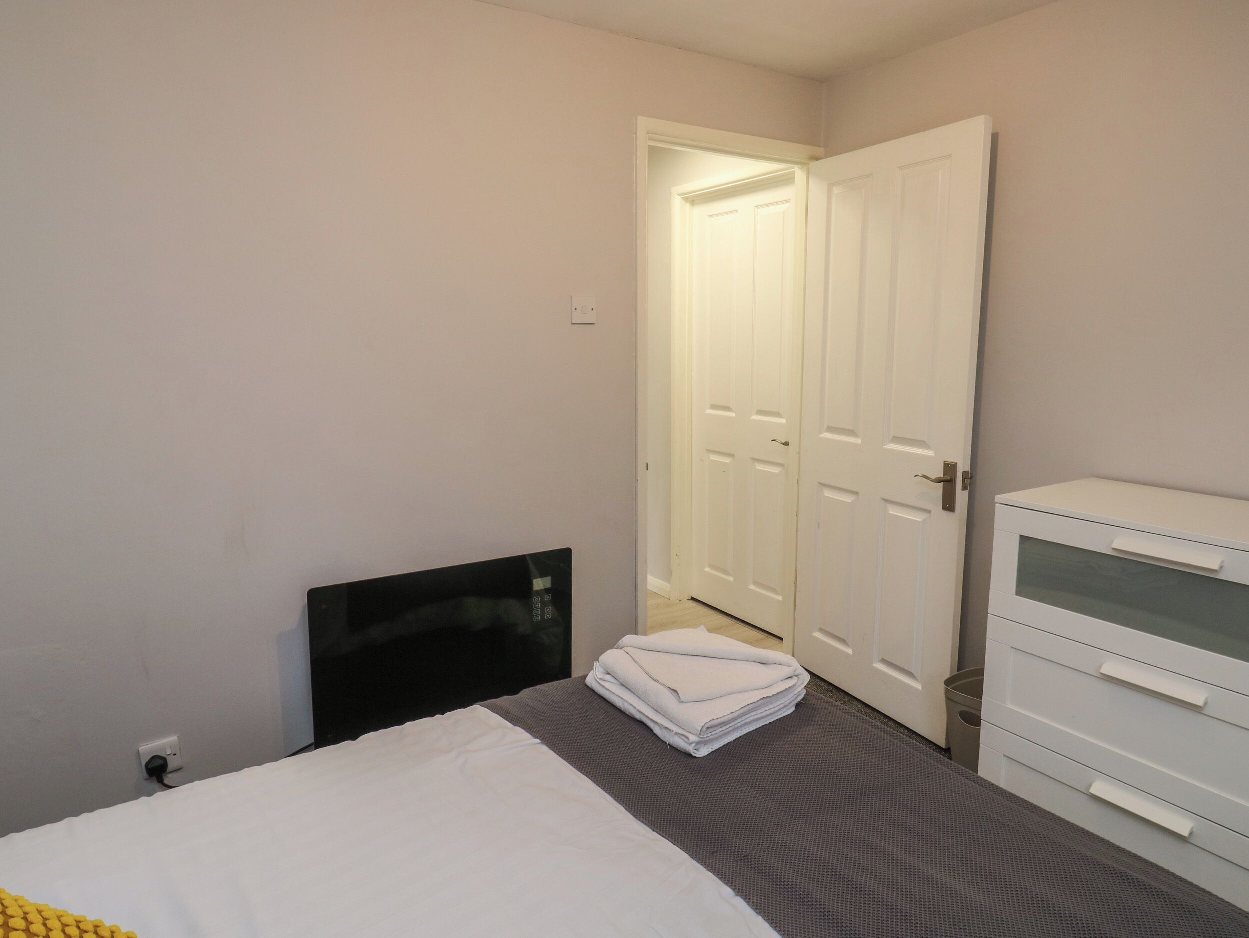 A bedroom with a bed, a dresser, and a closed door.