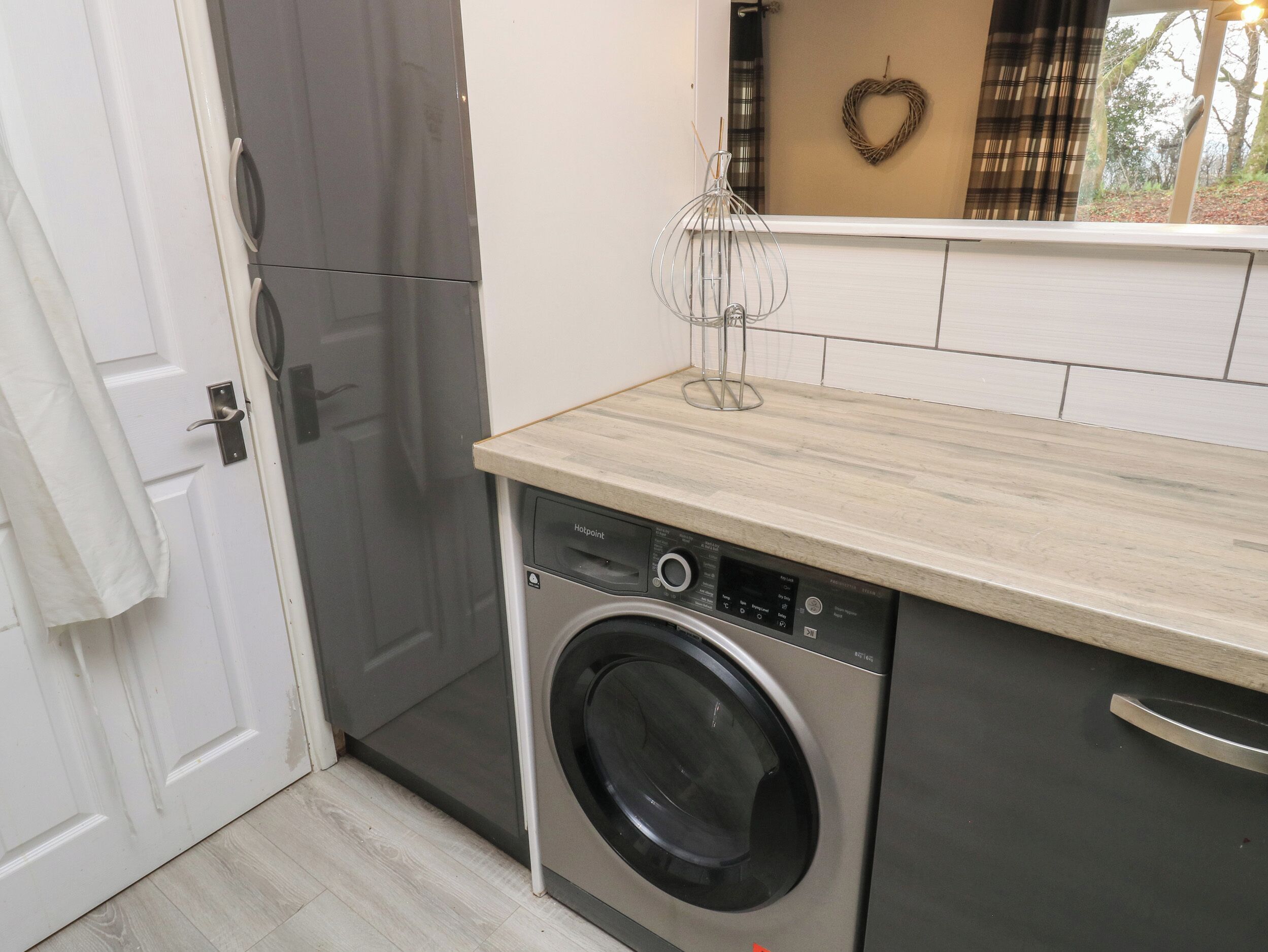 A compact kitchen with a washing machine, a refrigerator, and a wooden countertop.