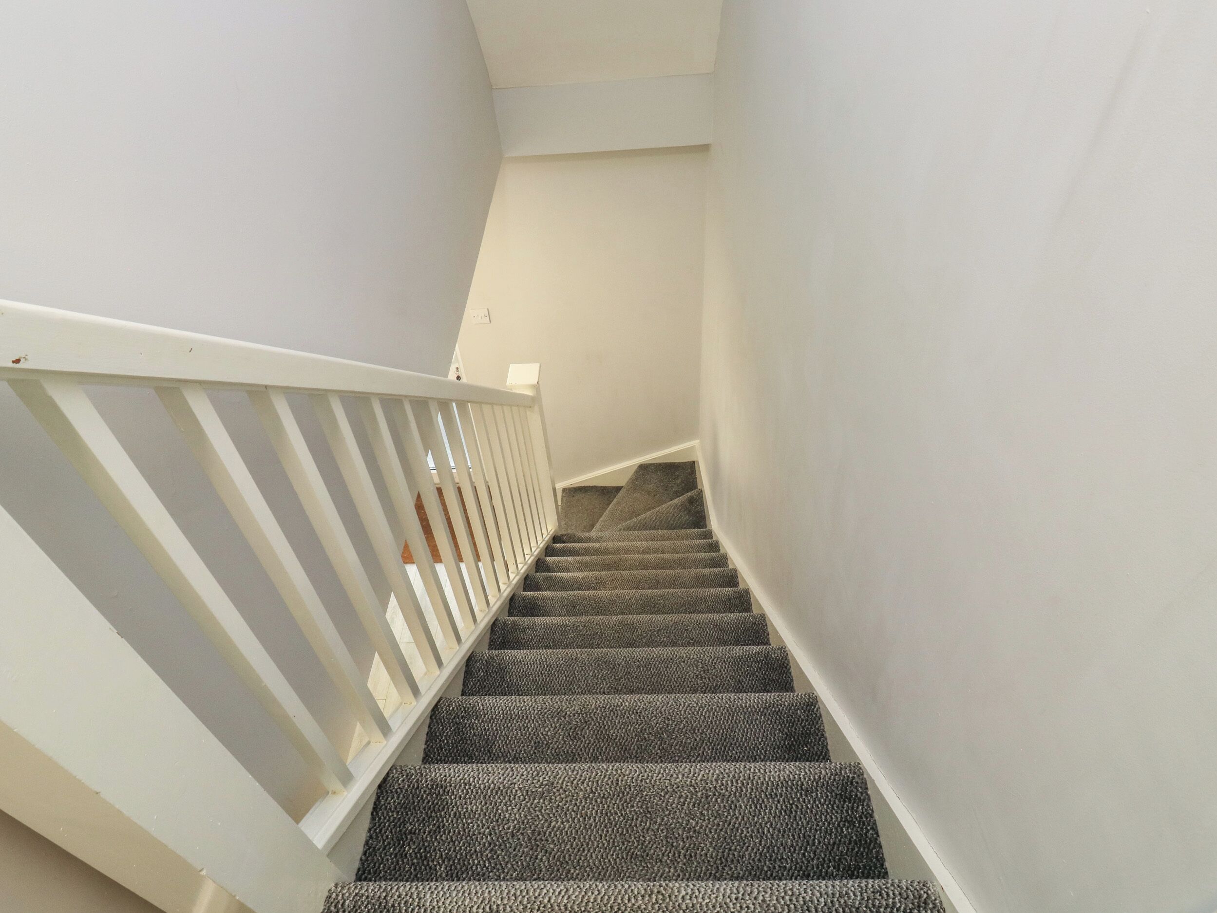 A staircase with carpeted steps and a white railing.